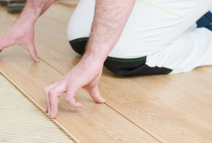 hands installing tongue and groove flooring