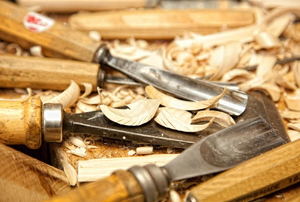 A pile of chisels surrounded by wood shavings. 