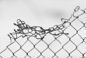 A broken, bent chain link fence.
