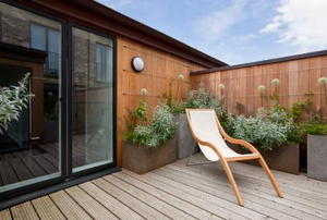 furnished outdoor deck with plants and a sliding glass door