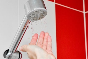 A shower head with water dripping out onto hand