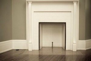 A brick fireplace with a coating of white paint and trim.
