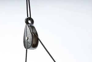 A black metal pulley with a thin rope stretched across it.