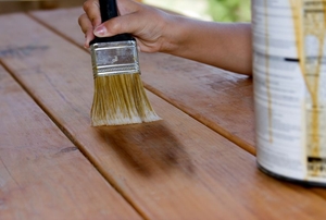 Use a paintbrush to stain a wooden deck.