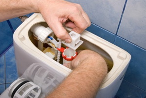 Reaching inside and open toilet tank to adjust components.