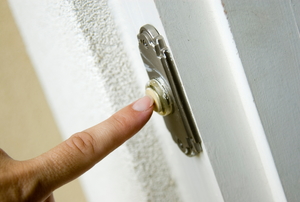 A woman presses a doorbell.