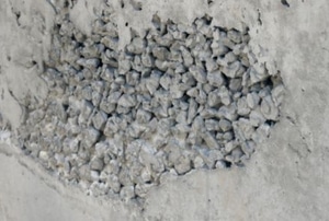 revealed stone honeycombing on rough concrete wall