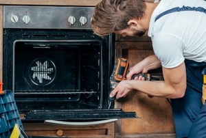 A man works on an oven.