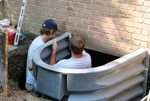 Two men install egress window wells.