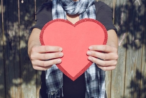 A woman holding a red paper heart.