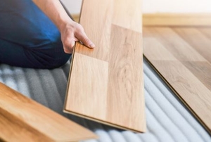 hands installing laminate wood flooring