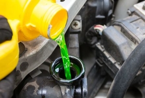 pouring green coolant in a car radiator