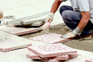 A man installs driveway pavers.