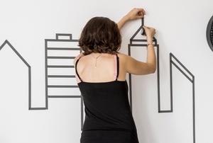 woman decorating wall with washi tape