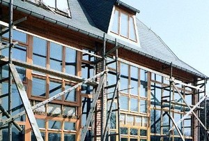 a house with scaffolding outside its large glass walls