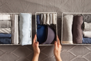 organizing folded clothes in canvas bins