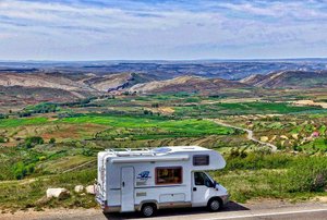 an RV on the road with green landscape in the distance
