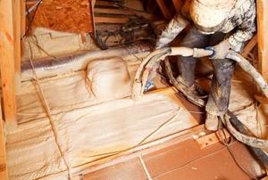 A worker pumping closed-cell foam insulation into an attic floor.