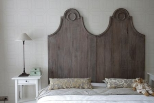 A rustic style headboard sits behind a bed.