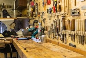 A workshop with tools hanging on the wall above a workbench.