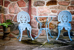A bistro set on a patio painted baby blue. 