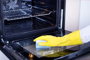 A woman cleans an oven.