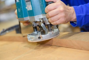 A close-up of a router in use on a piece of wood. 