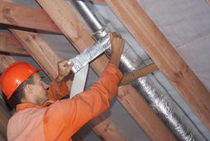 Sealing a crack in ducting in an attic.