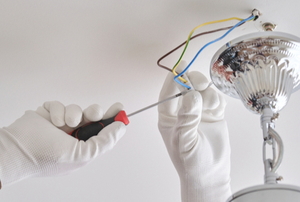 gloved hands installing light fixture wires