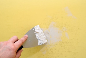 filling wall hole with putty knife and spackle