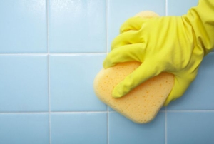 gloved hand wiping tile with a sponge