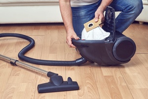 A woman uses a vacuum.