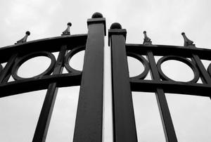 The ornamental tops of double metal gates across a driveway.
