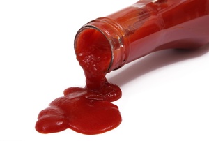 A spilled bottle of ketchup on a white background.