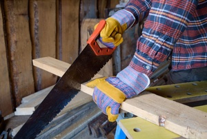 A man uses a hand saw.