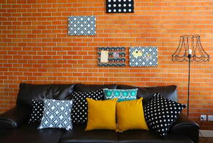 Colorful pillows on a sofa with brick wall in background.