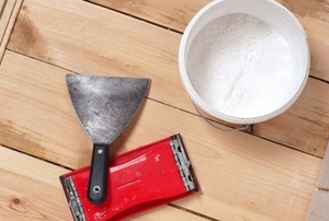 a Taping Knife on a wood table with a red instrument and white object next to it