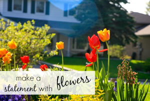 A flowerbed with a house in the background and the words "make a statement with flowers."