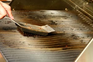 Scrubbing the grill with a wire brush.