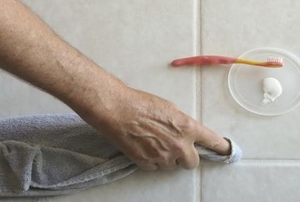A man wipes grout.