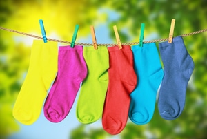 An array of colorful socks hanging outside from a clothes line.