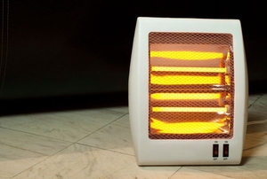 A small, electric space heater turned on to warm a tiled room.