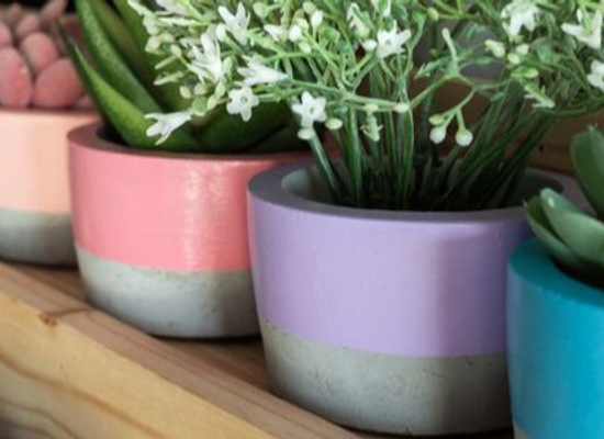 cement planters with colorful paint and small plants