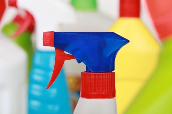 A close-up image of a spray bottle with other cleaning products in the background.