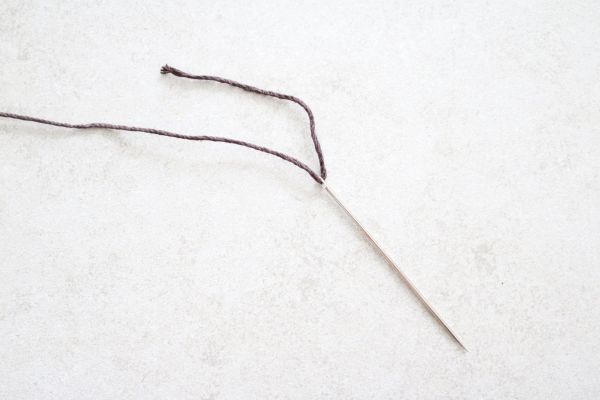 Threading cord through a needle.