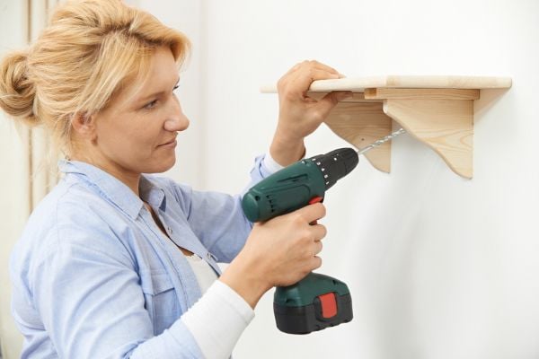 Woman mounting a shelf to the wall