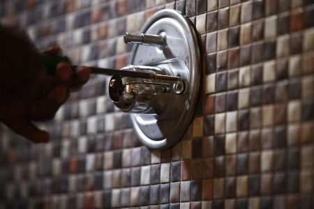 Tile back splash and faucet in a shower.