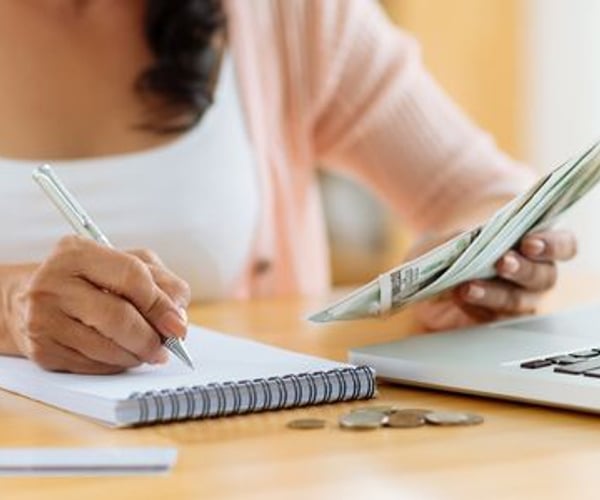 woman organizing money with notebook and computer