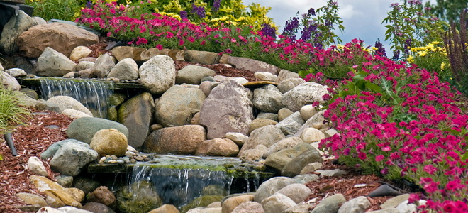Water flowing down a rock waterfall surrounded by colorful flowers