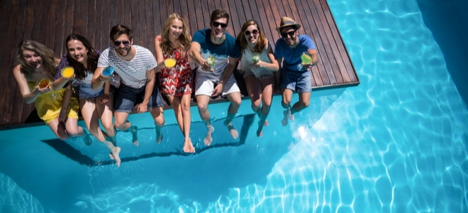young people sitting on the side of a pool with a transparent side panel